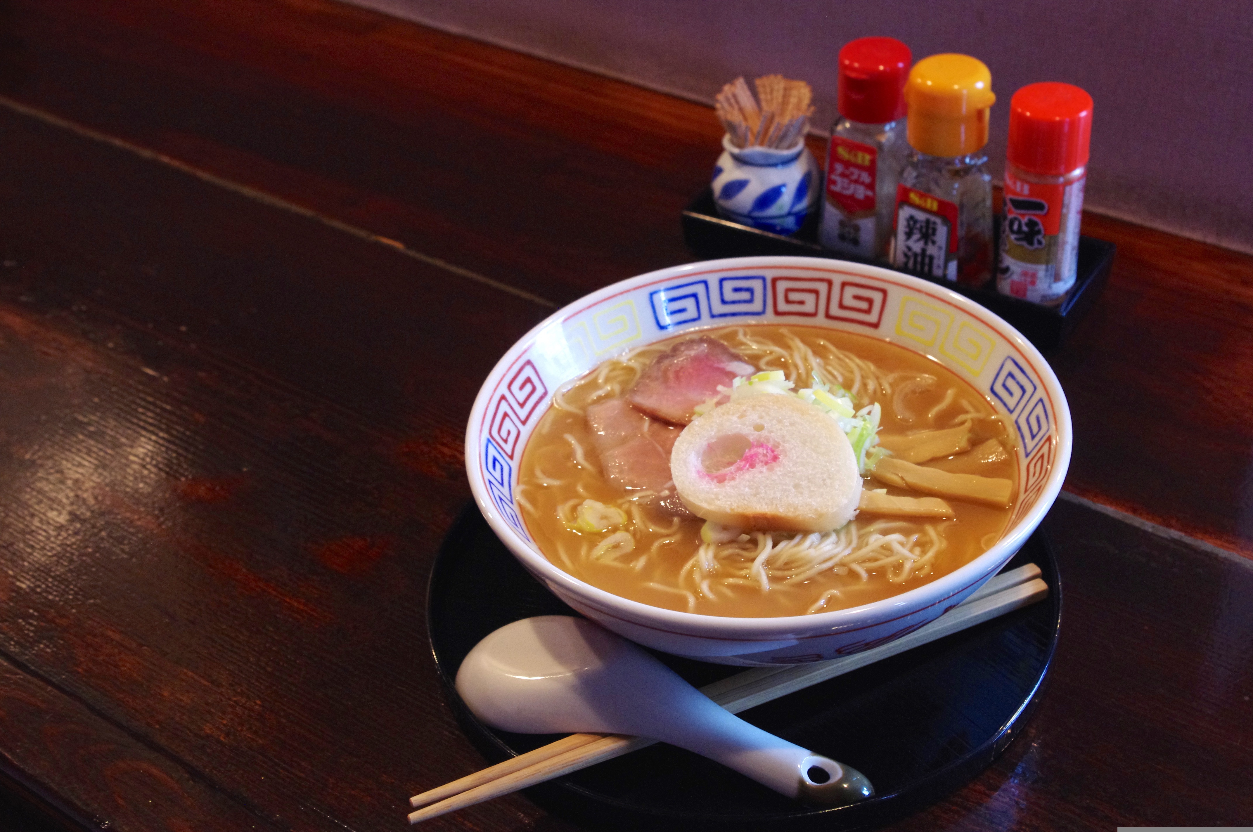 A bowl of ramen with condiments on a restaurant counter